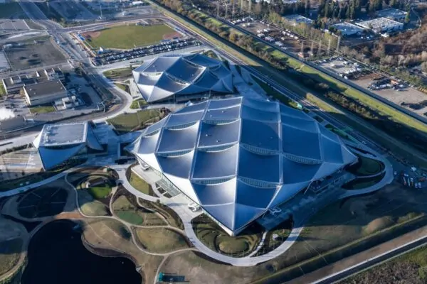 An aerial photo of Google's Bay View campus shows the wave-like form of the tensile canopy, covered in dragonscale solar panels and complimenting its surrounding landscape.  Dragonscale | SunStyle