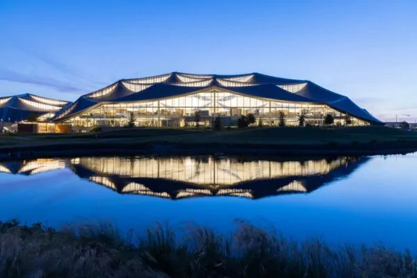 A photo of Bay View's larger building at twilight reflects in the stormwater retention pond, part of the water-positive design of the campus. Dragonscale | SunStyle