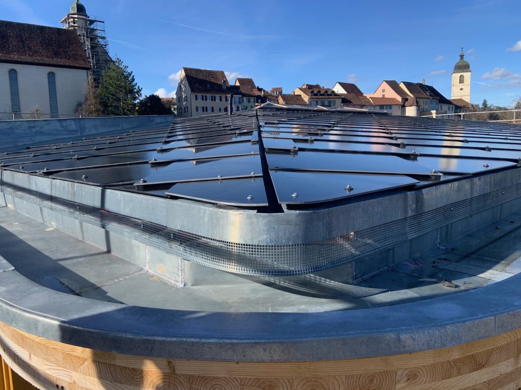 CH-2024 | 745 black | Jurassica Porrentruy_detail Jurassica, Porrentruy-Solardach-BIPV-SunStyle-geringe Neigung-Flachdach-mit Altstadt-Detail-Solarziegel-Abschluss